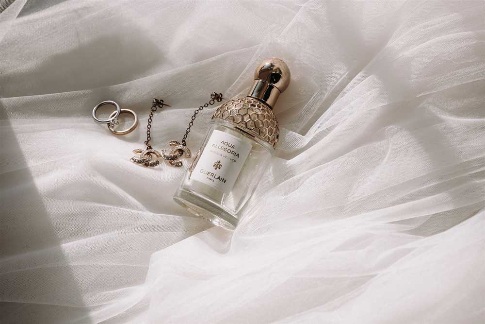 Hochzeitsdetails in Berlin von eleganten Hochzeitsaccessoires mit Guerlain Parfüm auf Tüll.