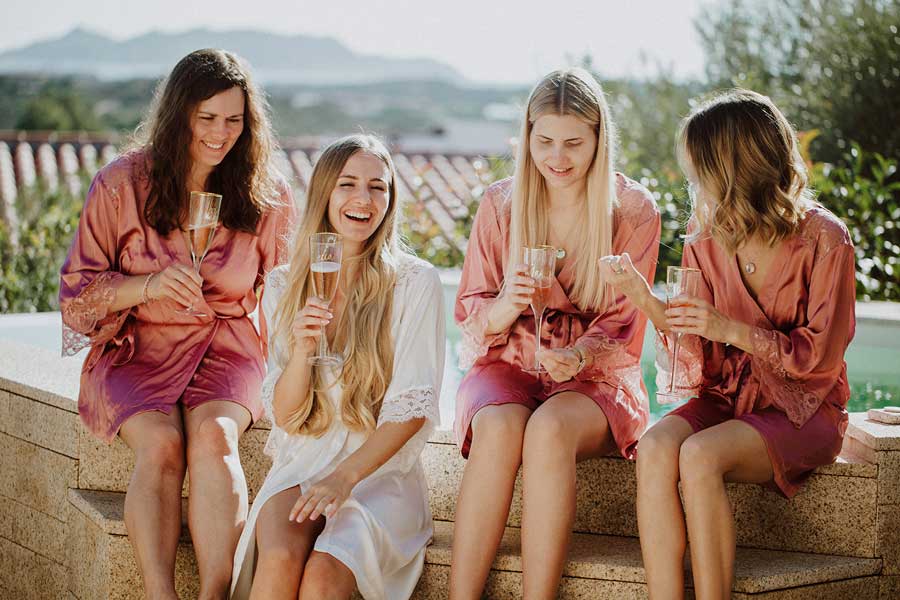 Hochzeit in Italien mit Fröhlicher Braut und Brautjungfern stoßen auf Terrasse an.