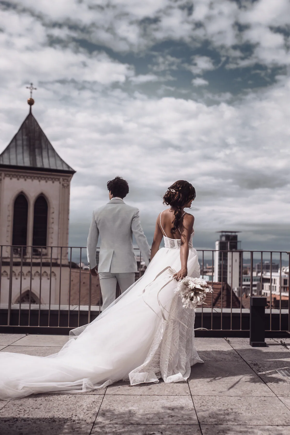 Ein Hochzeitspaar blickt von einer Dachterrasse über die Stadt