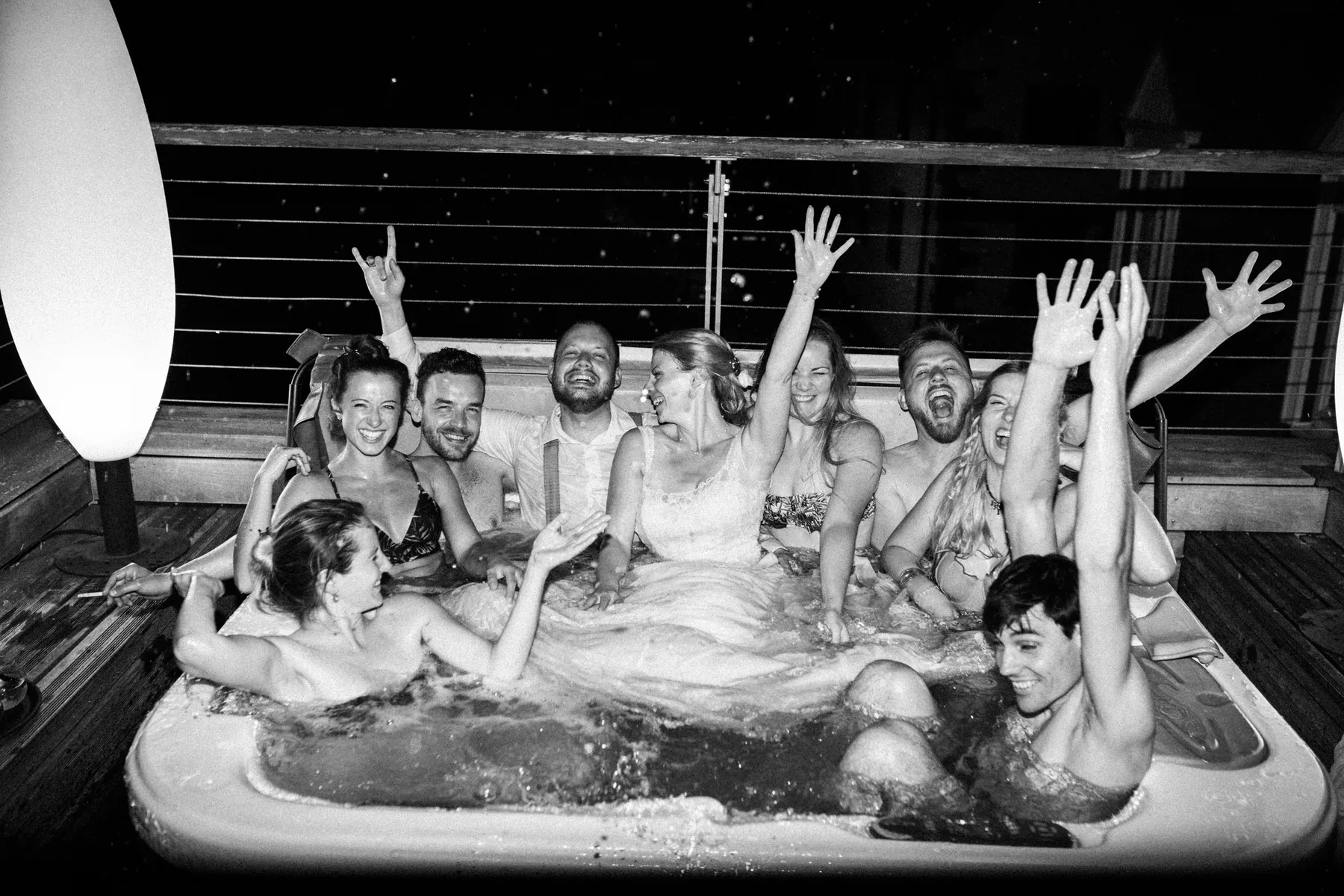 Eine große Hochzeitsgesellschaft feiert nachts gemeinsam in einem Whirlpool