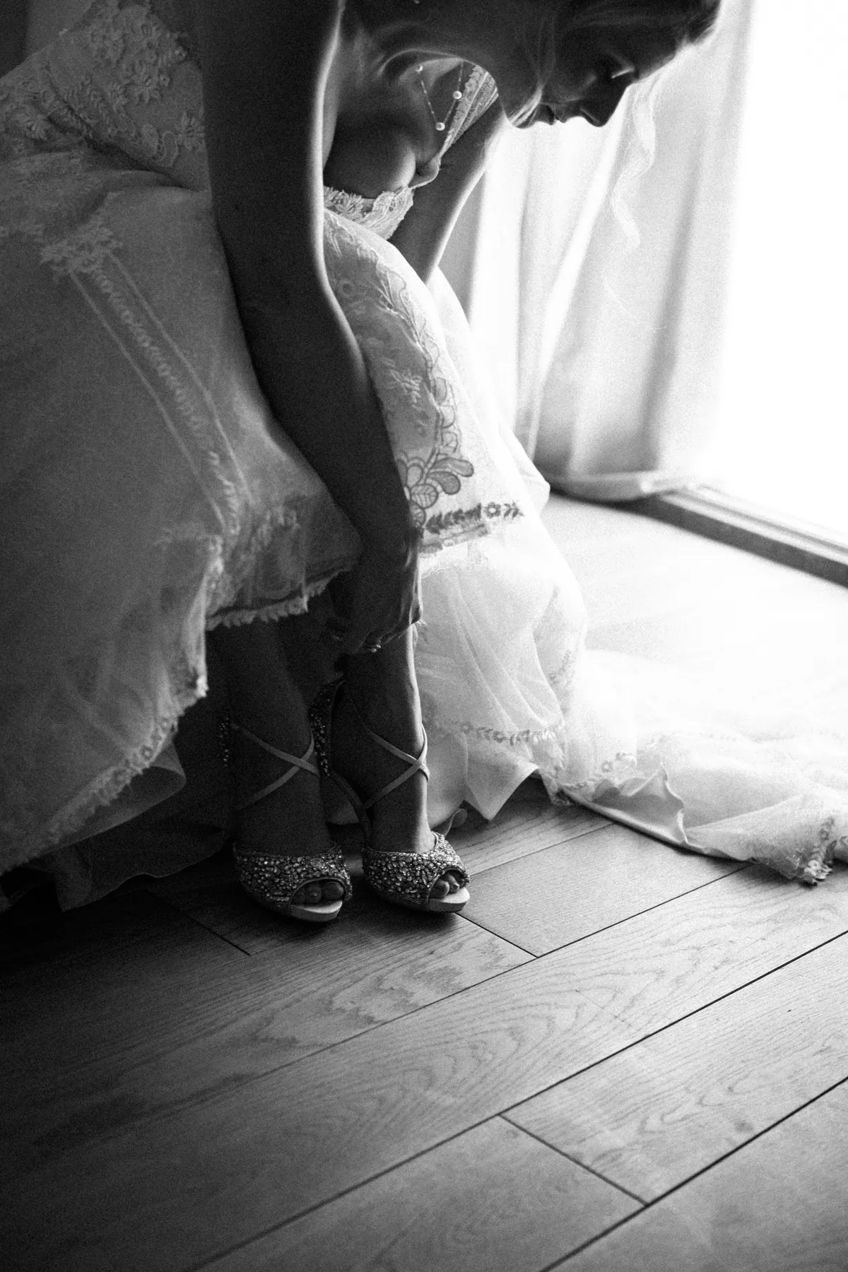 Eine Braut schließt beim Anziehen die Riemen ihrer Schuhe