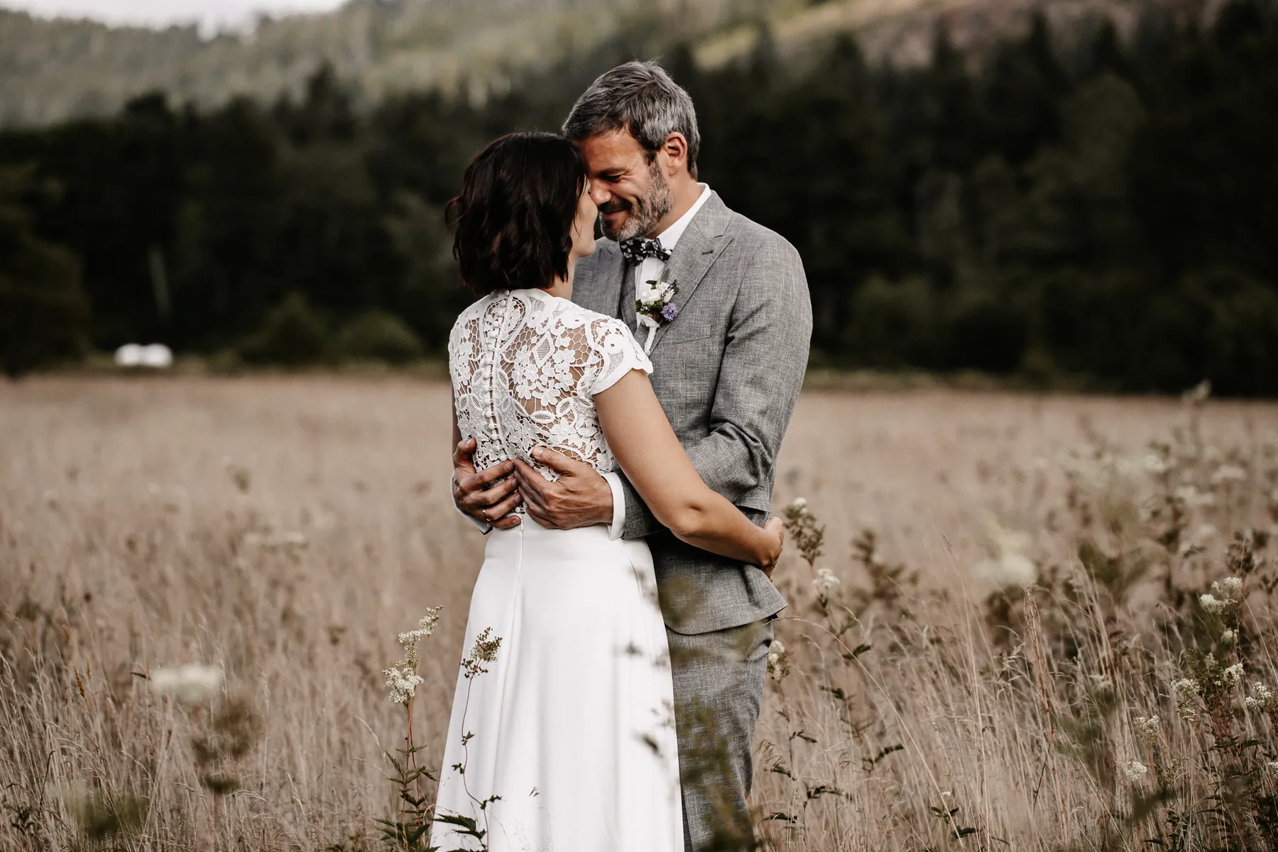Ein Hochzeitspaar steht Stirn an Stirn auf einer Wiese