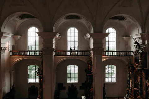 Brautpaar steht in einer hohen Kirche unter einer Bogenempore