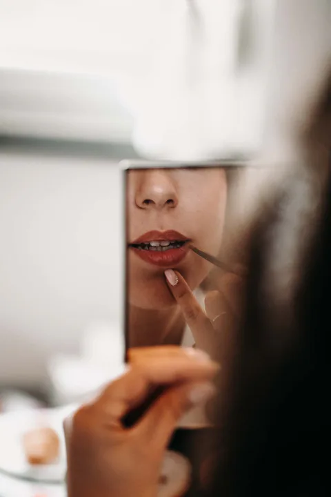 Braut trägt Lippenstift auf und betrachtet sich im Spiegel