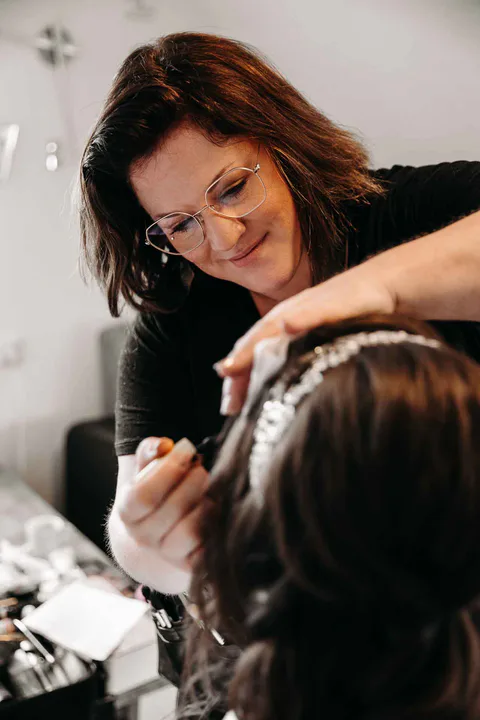 Friseurin arbeitet am Haar einer sitzenden Person