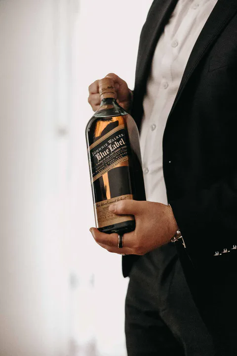 Mann im Anzug hält eine Spirituosenflasche